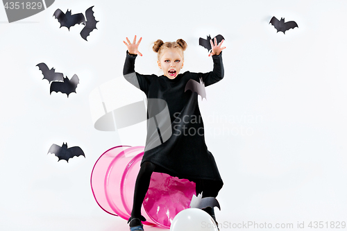 Image of Little girl witch in black dress over magical accessories. Halloween, the studio evening.