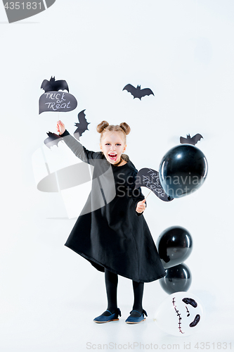 Image of Little girl witch in black dress over magical accessories. Halloween, the studio evening.