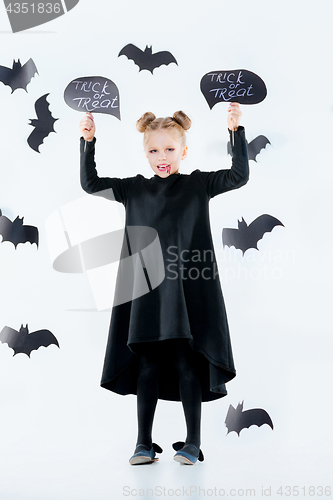 Image of Little girl witch in black dress over magical accessories. Halloween, the studio evening.