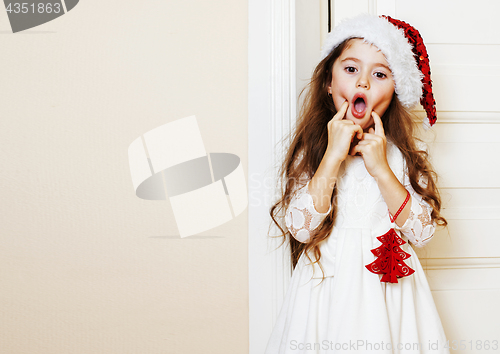 Image of little cute girl in santas red hat waiting for Christmas gifts. 