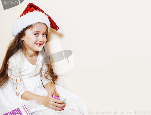 Image of little cute girl in santas red hat waiting for Christmas gifts. 