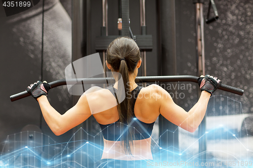 Image of woman flexing muscles on cable machine in gym
