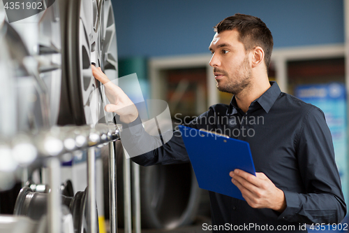 Image of auto business owner and wheel rims at car service