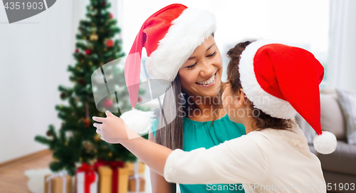 Image of happy mother and daughter in santa hats