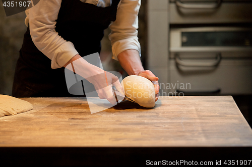 Image of baker portioning dough with bench cutter at bakery