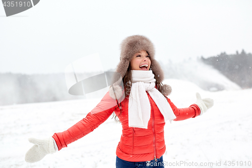 Image of happy woman in winter fur hat having fun outdoors