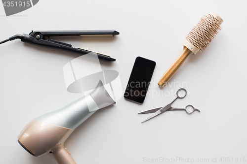 Image of smartphone, scissors, hairdryer, iron and brush