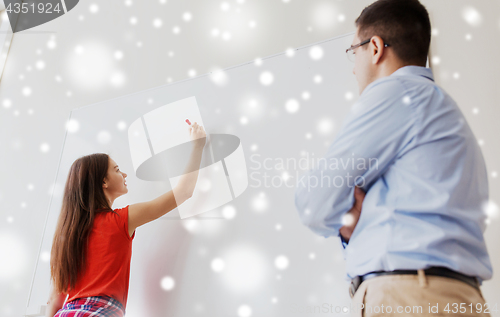 Image of student writing on board and teacher at school