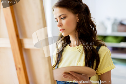 Image of student girl with easel painting at art school