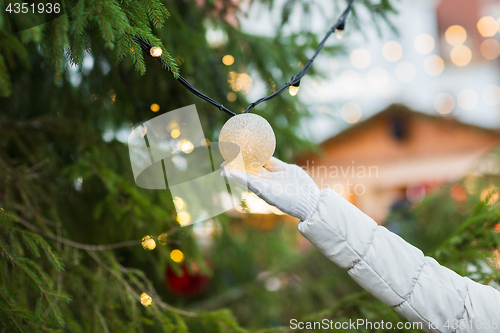 Image of close up of hand with christmas tree garland bulb