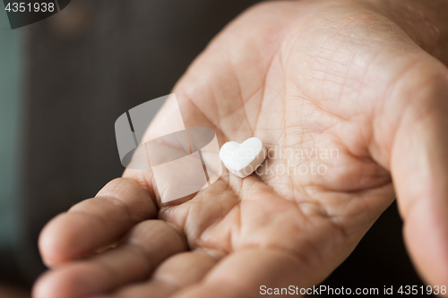 Image of close up of hand with heart shaped pill