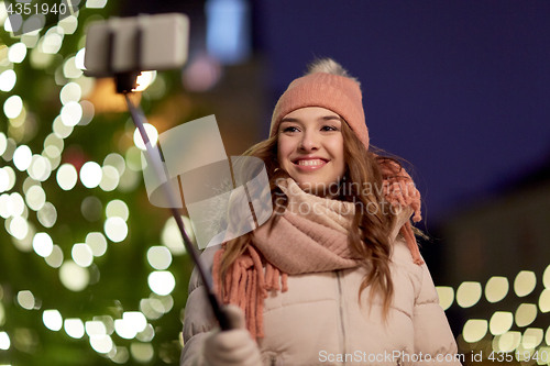 Image of young woman taking selfie over christmas tree