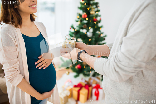 Image of husband giving christmas present to pregnant wife