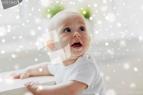 Image of happy little baby boy or girl holding to table