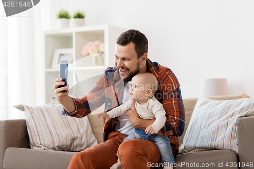 Image of happy father with baby boy taking selfie at home