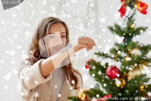 Image of happy young woman decorating christmas tree