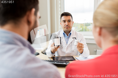 Image of doctor showing medicine to family couple at clinic