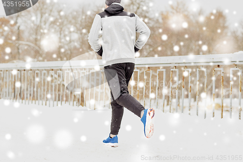 Image of man running along snow covered winter bridge road