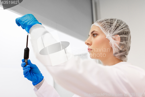 Image of woman with sulphuric acid in dropper at laboratory