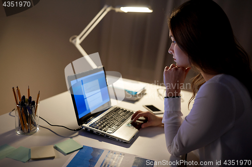 Image of businesswoman with laptop at night office