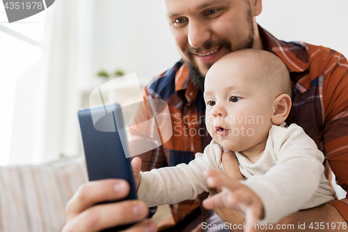 Image of happy father with baby boy taking selfie at home