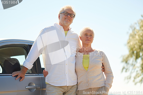 Image of happy senior couple hugging at car in summer