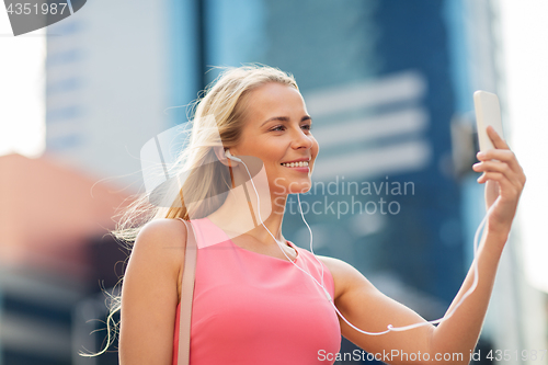 Image of happy young woman with smartphone and earphones