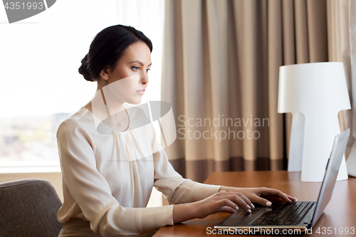 Image of businesswoman typing on laptop at hotel room