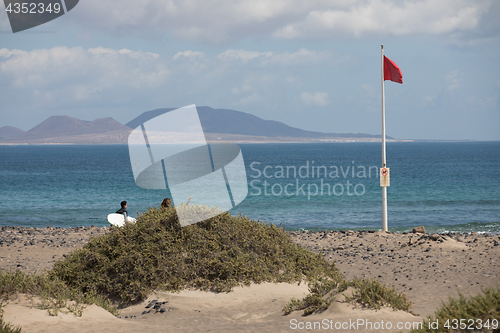 Image of The red flag weighs in the wind at Surfers Beach Famara on Lanza