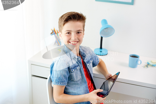 Image of smiling boy with tablet pc sitting at home desk