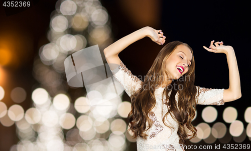 Image of happy young woman over christmas tree lights