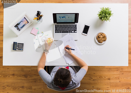 Image of woman with papers and cup of drink at office