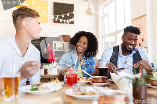 Image of happy friends eating and talking at restaurant