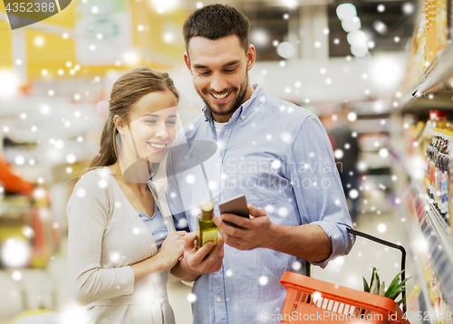 Image of couple with smartphone buying olive oil at grocery