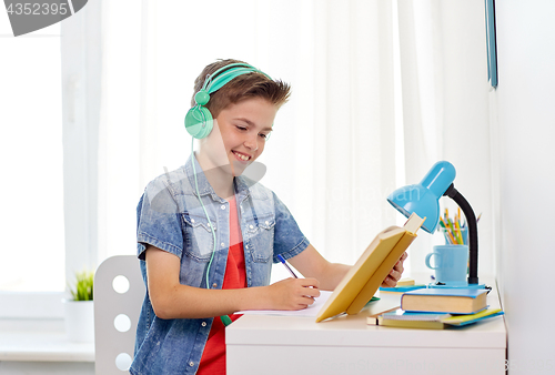 Image of student boy in headphones writing to notebook