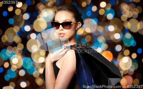 Image of happy woman in black sunglasses with shopping bags