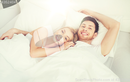 Image of happy couple lying in bed at home