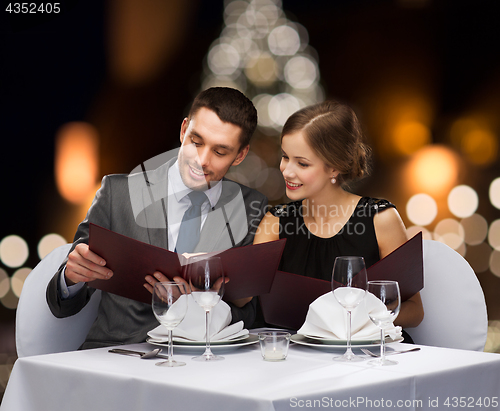 Image of smiling couple with menus at christmas restaurant