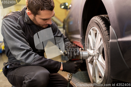 Image of auto mechanic with screwdriver changing car tire