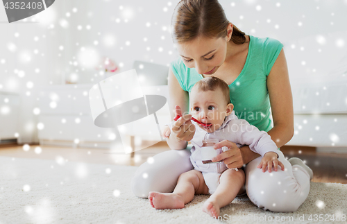 Image of mother with spoon feeding little baby at home