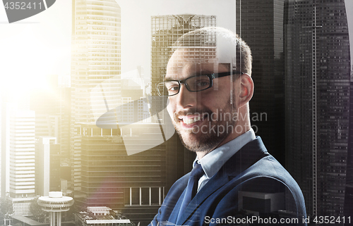 Image of smiling businessman in glasses over city buildings