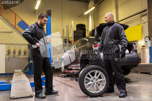 Image of auto mechanics changing car tires at workshop