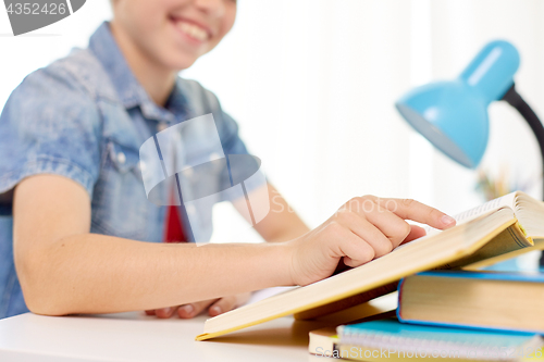 Image of student boy reading book at home table