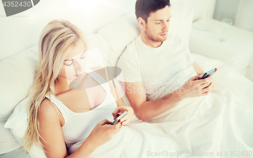 Image of couple with smartphones in bed