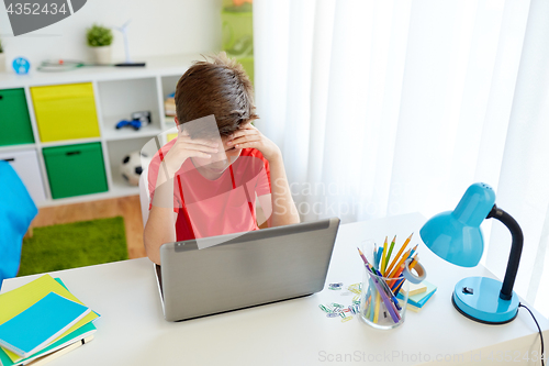 Image of tired student boy with laptop computer at home