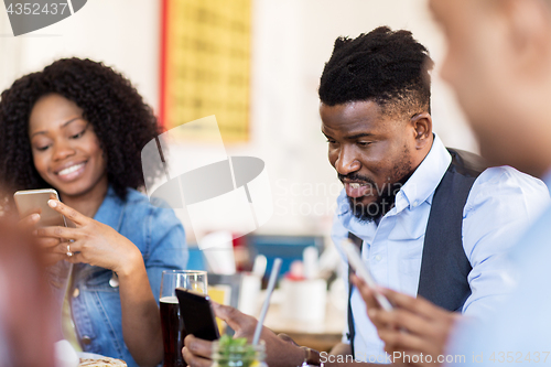 Image of happy friends with smartphones at restaurant