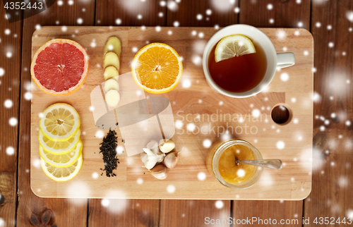 Image of ginger tea with honey, citrus and garlic on wood