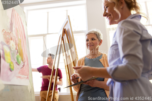 Image of artists discussing painting on easel at art school