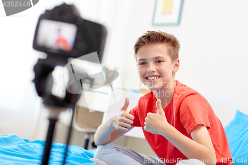 Image of happy boy with camera recording video at home