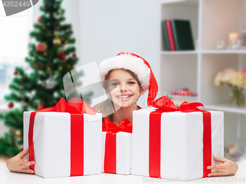 Image of smiling girl in santa hat with christmas gifts